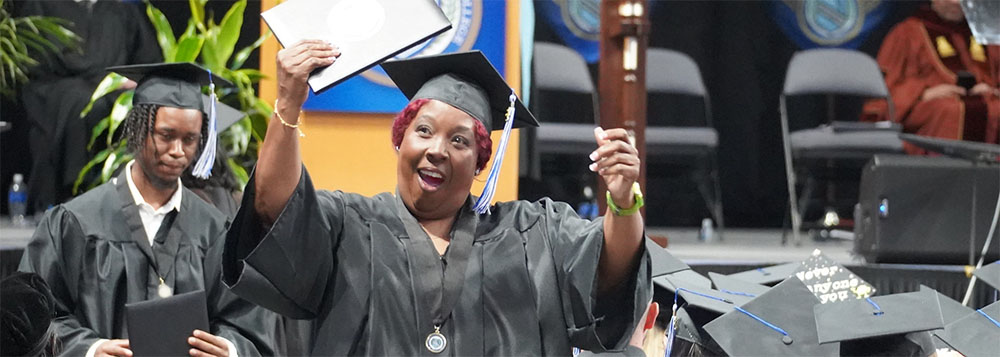 2023 Commencement Recap - Happy Grad holding diploma in the air